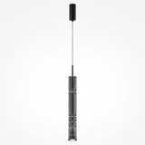 The Ordo LED Long Pendant Light features a sleek black finish with cylindrical smoky glass, vertical ridges, and an integrated LED. It hangs from a thin black cord attached to a matching ceiling mount, creating depth against a plain white background.