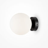 The Basic form Small Frosted Ball Wall Light in black has a modern design with a frosted glass globe and sleek metal base, attached to the wall with two subtle screws.