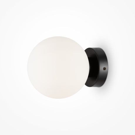 The Basic form Small Frosted Ball Wall Light in black has a modern design with a frosted glass globe and sleek metal base, attached to the wall with two subtle screws.