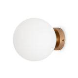 The Basic form Medium Frosted Ball Wall Light - Gold features a frosted glass globe mounted on a circular gold base. Its minimalist design blends contemporary and classic styles, making it perfect for diverse interior settings.