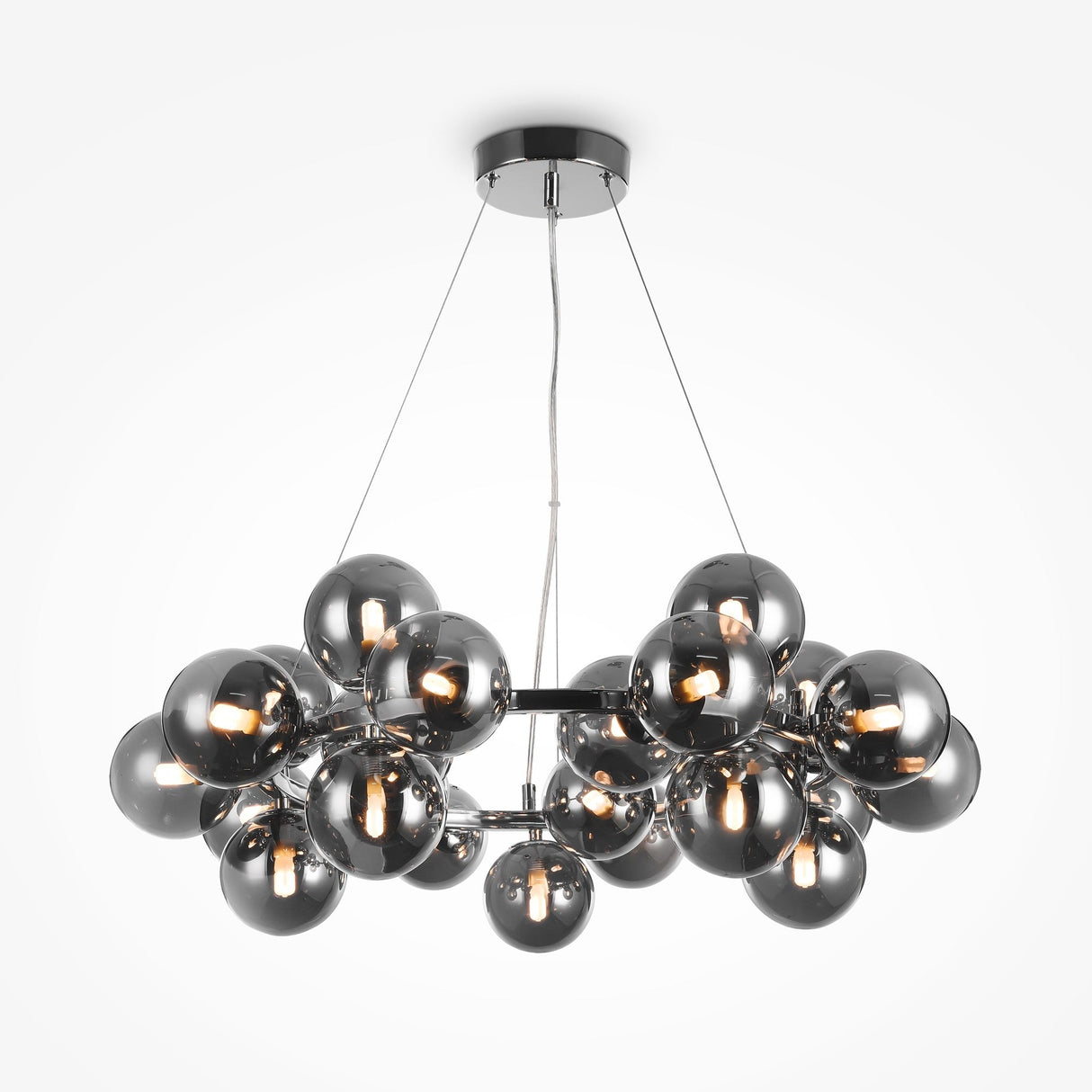The Dallas 25 Light Suspension in Chrome features metallic spheres with small bulbs and smoky glass accents. These elegant spheres cluster together, suspended by thin cables from a circular ceiling mount, showcasing a sleek and modern design.