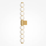 The Amulet LED Vertical Wall Light features a gold frame with ribbed glass spheres. The textured spheres create a stunning effect as the square gold backplate mounts it evenly, providing balance to the elegant design.