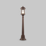 The Salamanca 1 Light Pillar Lantern - Brown features a vintage style with a tall bronze post and cylindrical lantern, emitting soft light through clear glass. Its sturdy and ideal for gardens or pathways against any gray backdrop.