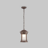 The Salamanca Outdoor Pendant Light - Brown features a lantern-style design hanging from the ceiling by a sturdy chain. It includes a cylindrical frosted glass shade encased in decorative bronze, combining retro aesthetics with durable construction.