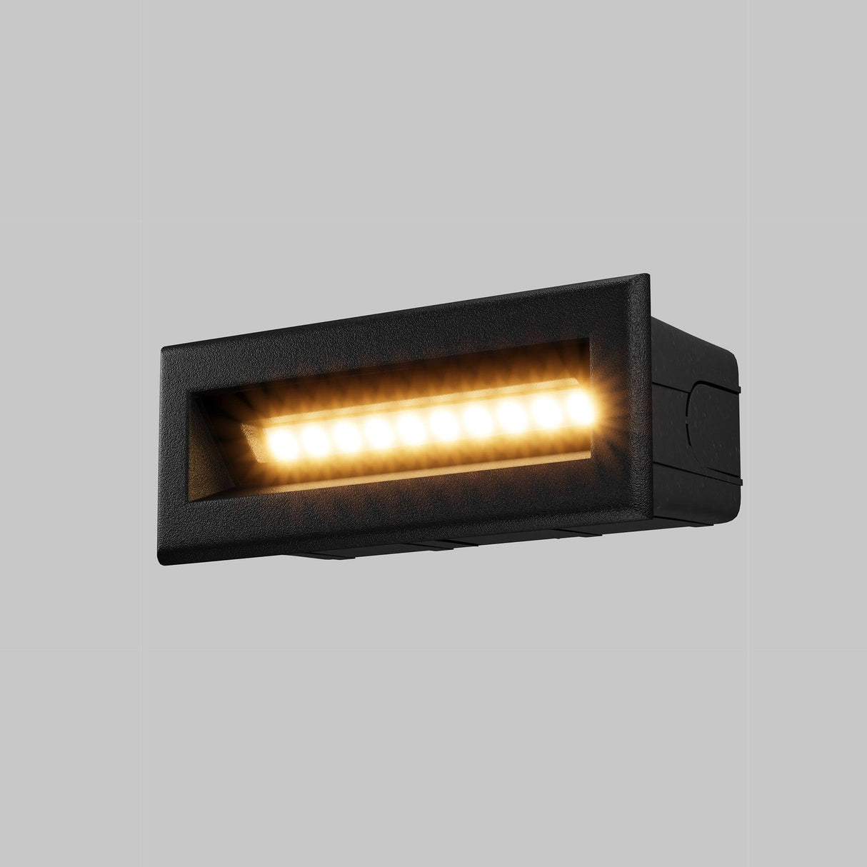 The Bosca Outdoor LED Long Recessed Wall Light - Black features a durable IP65-rated rectangular design, perfect for outdoor use, with a sleek black frame and warm yellow LED bulbs against a gray background.
