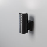 The Bowery Outdoor 1 Light Wall Light - Black (O583WL-01B) is a minimalist wall-mounted cylindrical sconce with a textured top and smooth bottom. Its modern design, coupled with an IP54 rating, effortlessly enhances any setting by casting subtle shadows on plain walls.