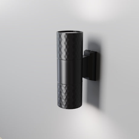 The Bowery Outdoor 2 Light Wall Light (O583WL-02B) is a black, modern metal fixture with a textured diamond pattern, mounted on a gray wall. Its cylindrical design emits light from both ends, making it an ideal sleek and minimalistic choice for any outdoor setting.
