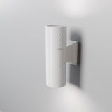 The Bowery Outdoor 2 Light Wall Light (O583WL-02W) in white features a cylindrical design with a textured surface, mounted on a light gray wall. This corrosion-resistant fixture emits light from the top and bottom, providing soft illumination for modern exteriors.