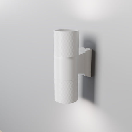 The Bowery Outdoor 2 Light Wall Light (O583WL-02W) in white features a cylindrical design with a textured surface, mounted on a light gray wall. This corrosion-resistant fixture emits light from the top and bottom, providing soft illumination for modern exteriors.