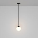 The Luna LED Recessed Globe Pendant Light 10cm 3000K in black and white showcases a minimalist black cord design with a spherical white lampshade, providing a soft glow and energy efficiency against a neutral gray background.