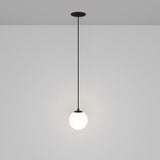 The Luna LED Recessed Globe Pendant Light 10cm 4000K - Black & White features a minimalist design with a black rod and white globe, casting an energy-efficient soft glow against a gray background that embodies contemporary style.