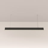 The Points LED Linear Suspension Light - Black is suspended elegantly by two thin wires from the ceiling, boasting an adjustable height for versatility while casting a gentle glow beneath it against a simple white background.