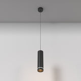 The Orlo LED Pendant Light 3000K in black, featuring a sleek cylindrical design and adjustable suspension, hangs stylishly from the ceiling, casting a subtle glow on the neutral wall while highlighting minimalist simplicity and elegance.