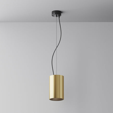 The Efir LED Pendant Light 33W - Matte Gold features a cylinder shade, suspended by a black cord and mount. This energy-efficient fixture complements a plain white wall with a gray ceiling, merging modern style with sustainability.