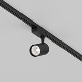 The Vuoro S LED Single Phase Unity Track Spotlight, a sleek black 10W cylindrical fixture mounted on a ceiling track, features modern energy-efficient 4000K lighting that brightly illuminates the space below.
