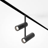 The Elti Duo LED Magnetic Exility Track Spotlight 24W 3000K - Black is a sleek, modern ceiling light with two cylindrical spotlights on a central rod, ideal for contemporary interiors. Each spotlight elegantly illuminates from the white ceiling with its minimalist design.
