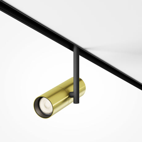Close-up of an Elti CCT Dimmable LED Magnetic Exility Track Spotlight 12W 2700-6000K in black and brass. The cylindrical matte gold lamp, on a black track system, offers adjustable and focused smart lighting on a white ceiling.