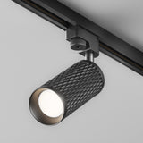 Close-up of the Focus Design Single Phase Unity Track Spotlight in black, showcasing its sleek cylindrical design on a ceiling track. The GU10 base emits a bright glow, elegantly illuminating the room.