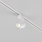 The Vuoro S 3-Circuit Trinity Track LED Spotlight 10W 3000K in white is mounted on a ceiling rail, providing focused downward lighting with its modern cylindrical design against a neutral background.