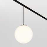 The Luna LED Exility Magnetic Track Pendant Light 5W 3000K - Black showcases a round, frosted glass globe on a sleek dark rod, casting ambient light on a plain, light gray wall to highlight its minimalistic design.