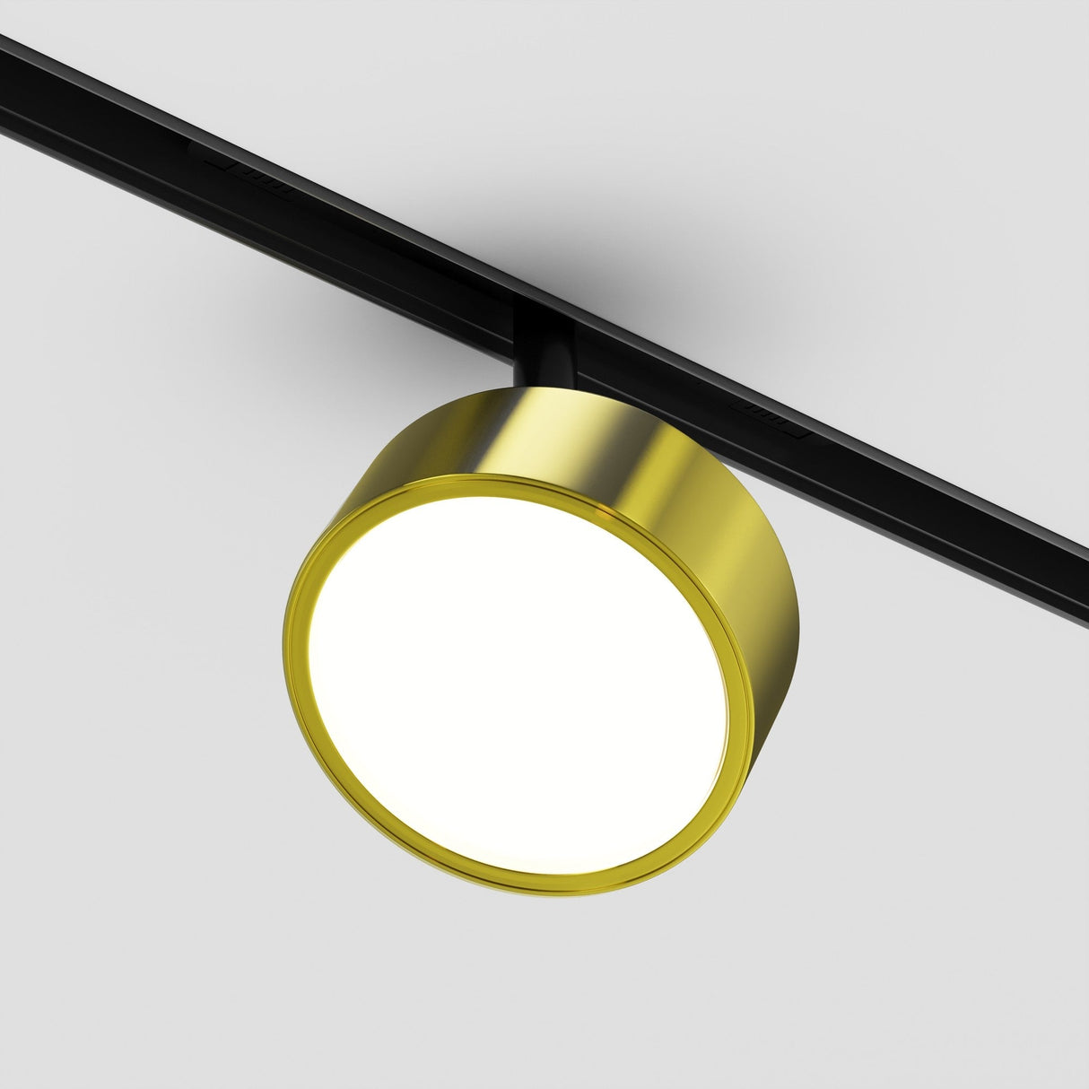 A Rado 18W CCT LED Dimmable Magnetic Exility Track Spotlight, featuring a black track and brass finish, is mounted on a white ceiling. It emits an adjustable bright glow with smart tech features, reflecting minimalistic modern design.