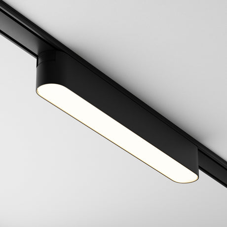 Close-up of the Basis LED Linear Track Light for Magnetic Tracks Radity 12W 3000K - Black. The sleek, rectangular design emits a bright glow against the white ceiling. Its minimalist look is modern and unobtrusive, with magnetic tracks for easy installation and adjustment.