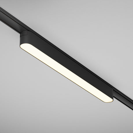 The Basis LED Linear Track Light, Radity 16W 3000K in black, is ceiling-mounted with a sleek rectangular bulb design. It uses magnetic tracks to create a warm glow, ideal for minimalist spaces.