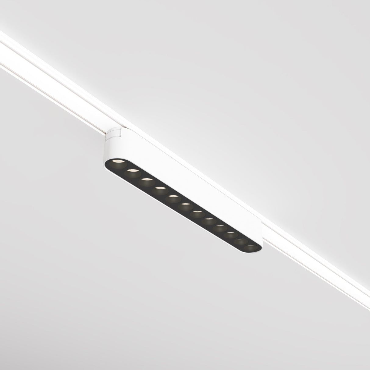 The Points LED Linear Track Light for Magnetic Tracks Radity 12W 3000K in white offers a minimalist touch with nine circular bulbs on magnetic tracks, mounted on a sleek ceiling. This modern fixture emits a cozy warm color temperature, ensuring both simplicity and functionality.