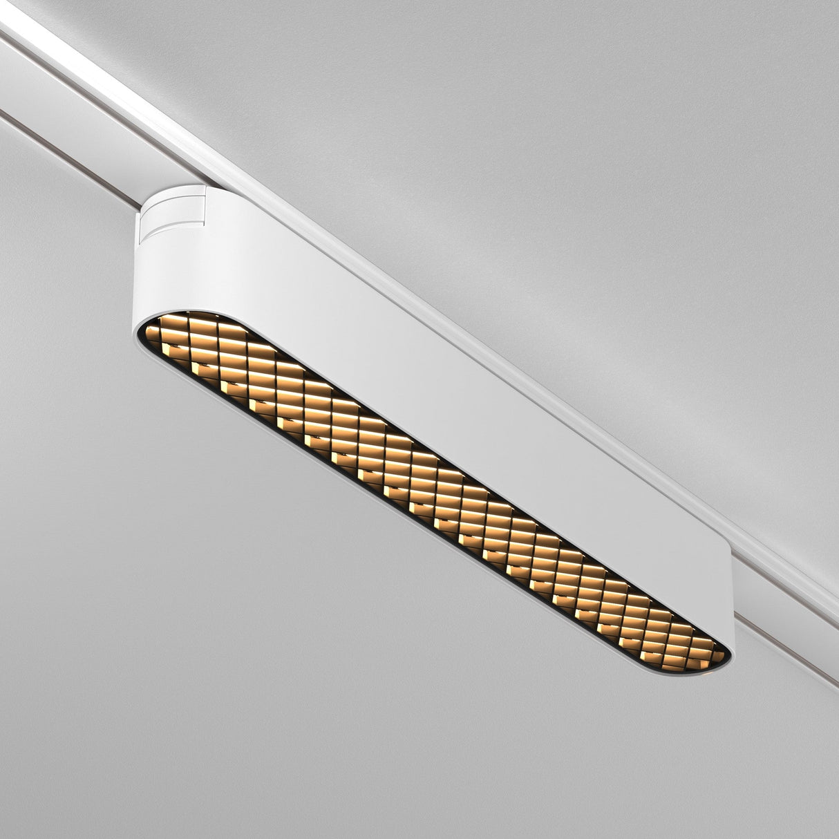 The Basis Grid LED Linear Track Light, seamlessly mounted on the Magnetic Tracks Radity, features a 12W white casing with a grid-like diffuser that emits a warm 3000K glow, elegantly blending into the plain grey ceiling.