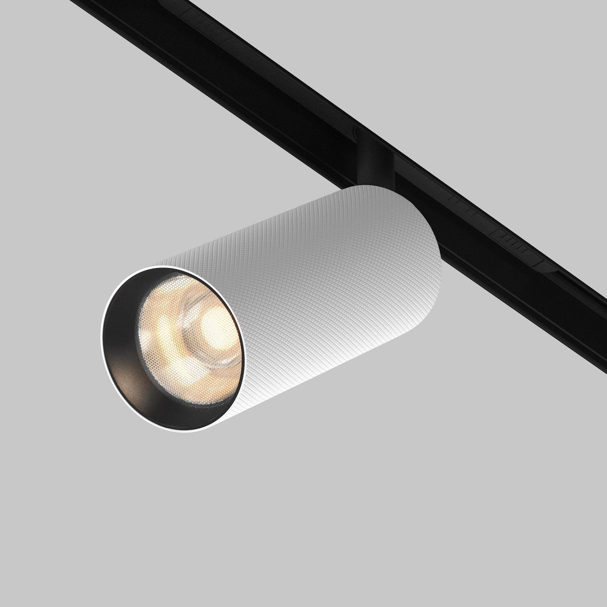 A cylindrical white spotlight with a diamond-textured lampshade is mounted on a black track against a light gray background. The Artisan LED Magnetic Exility Track Spotlight 12W 3000K, in black and white, is on, emitting a warm glow.