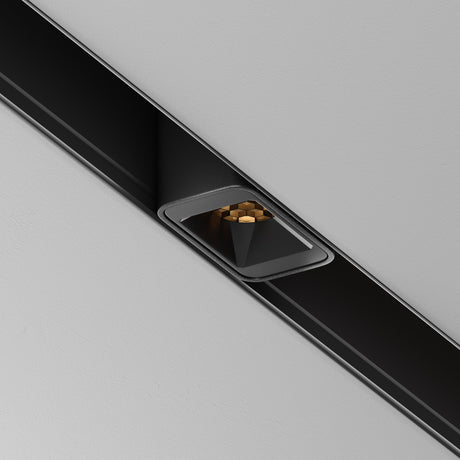 A close-up of the Points S LED Magnetic Exility Track Downlight 2W 3000K - Black, featuring a modern recessed geometric design. The triangular housing integrates a HoneyComb filter and gold cylinders, offering exquisite accent lighting on the gray ceiling.