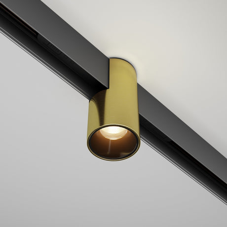 The Alfa LED Magnetic Exility Track Downlight 7W 3000K in brass, with its modern cylindrical design, is mounted on a sleek black track against a white ceiling. This accent lighting emits a soft glow downward, enhancing the elegance of any room.