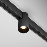 The Alfa LED Magnetic Exility Track Downlight 7W 3000K in black is mounted on the ceiling, featuring a sleek cylindrical spotlight design. It emits warm light that enhances its minimalist look against a white ceiling, exemplifying contemporary lighting at its finest.