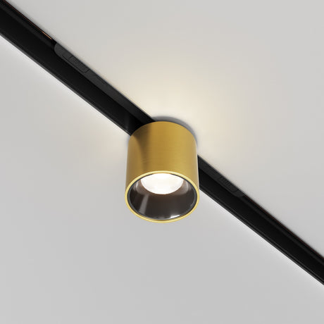 The Alfa S LED Magnetic Exility Track Downlight 7W 3000K in brass finish features a cylindrical gold-toned metal casing on a black track, providing soft illumination that enhances room elegance with its modern design.