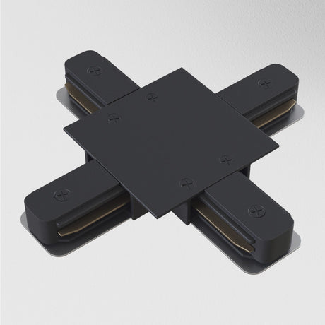 A modern abstract sculpture, the Unity Tracks Recessed X-Shaped Connector in black metal, is mounted on a white wall. It features a central square with extending arms like an X, showcasing rounded edges and visible screws.