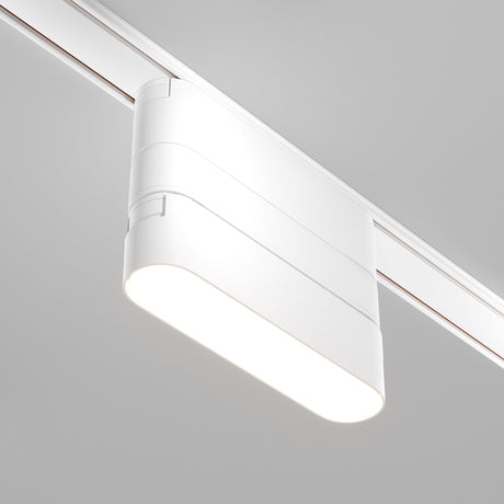 Close-up of the Radity Magnetic Track Short Adaptor in white, an illuminated LED light fixture on a ceiling track, boasting a sleek, minimalist design perfect for contemporary interiors. It attaches easily to a linear rail system along the ceiling.
