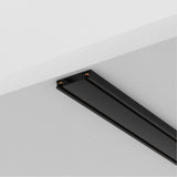 The Radity Magnetic Surface-Mounted Track 2m in black is perfect for modern interiors, mounted on a white ceiling with a sleek design and two exposed copper connections on one end, offering versatile lighting solutions.