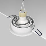 A close-up of the Atom Single Tilt Round Recessed Downlight - White (DL023-2-01W) being installed in a ceiling. It features a minimalist design with a cylindrical base and spring-loaded clips for secure placement, plus two wires on top for electrical connection.