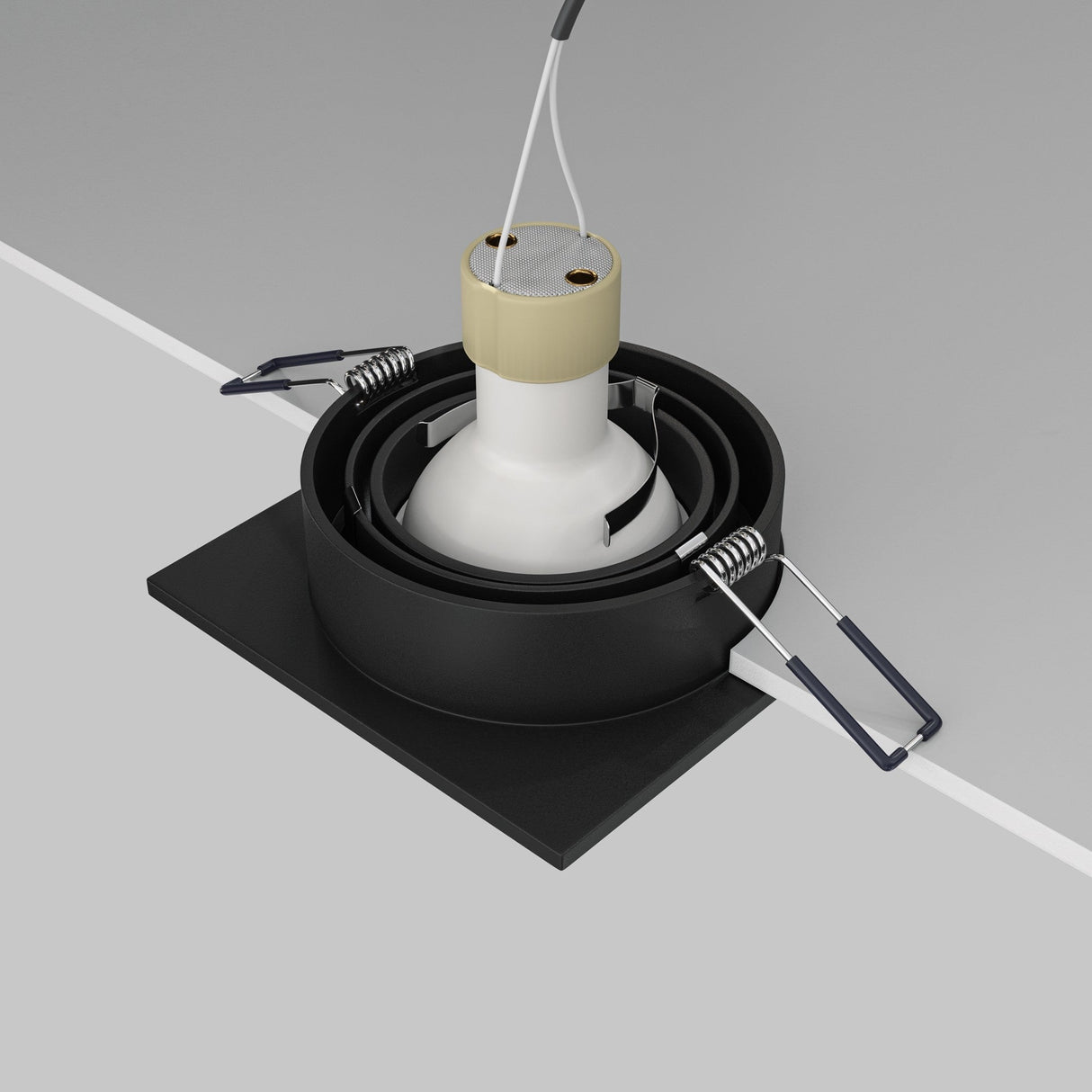 Close-up of an Atom Single Tilt Square Recessed Downlight in black, showcasing metal springs for installation. The fixture is partially placed in a ceiling cutout with hanging wires and features an adjustable tilt mechanism for directional lighting, but lacks a bulb.