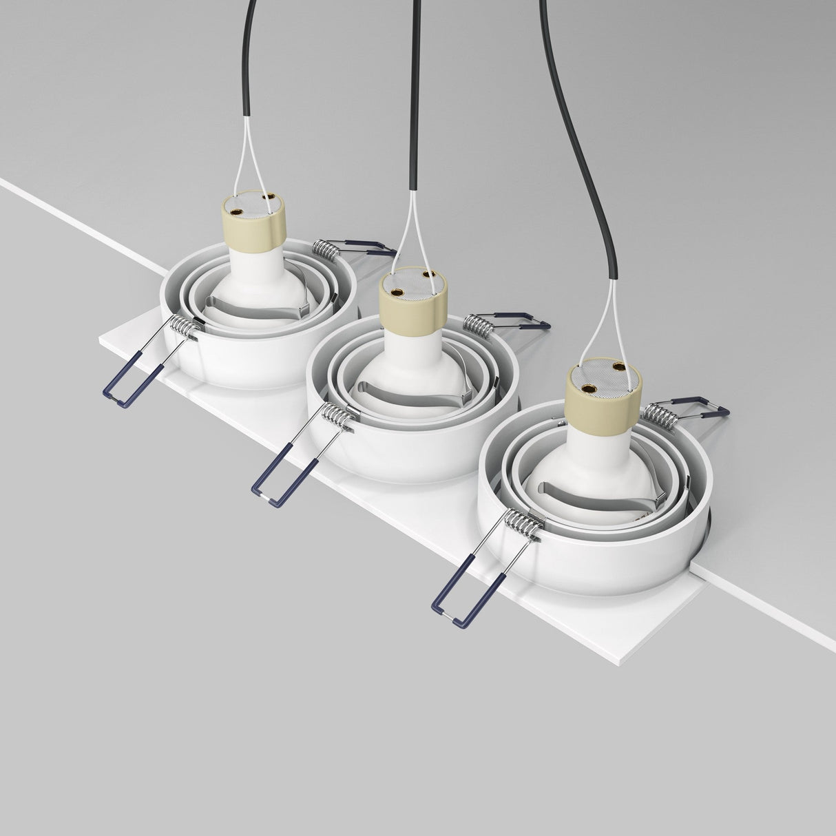 Three Atom Tri Tilt Rectangular Recessed Downlights are mounted on a white ceiling in a row, each suspending a black wire. Their modern design and sleek silhouette stand out against the gray background, adding to the contemporary aesthetic. Bulbs not included.