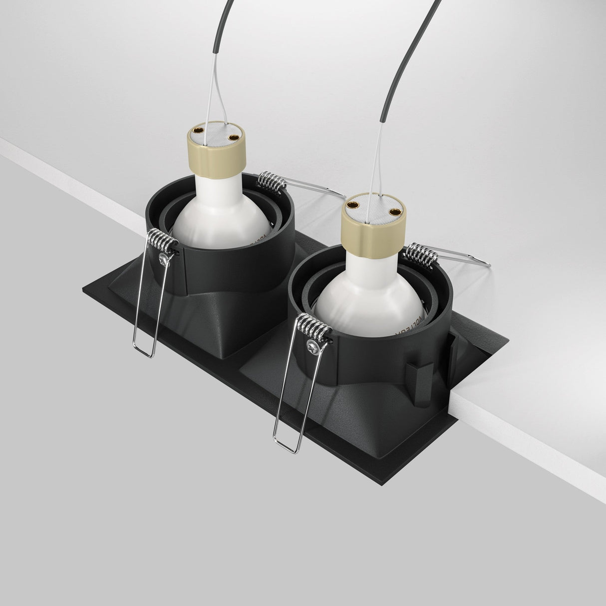 Two Dot Twin Tilt Recessed Downlights in black are shown partially installed in a white surface. These energy-efficient LED fixtures feature white bulbs, visible spring clips, and wires extending from the top.