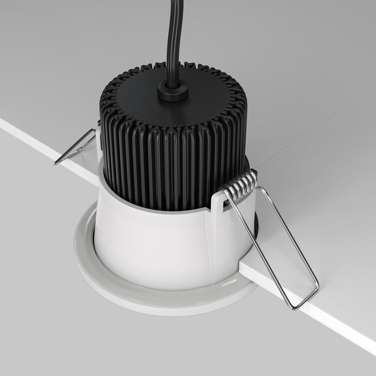 The Zoom LED Round Recessed Downlight 6W 4000K - White is partially installed in the ceiling with a black heat sink and an upward wire. Its light offers excellent CRI, and metal spring clips ensure it sits flush against the white ceiling securely.