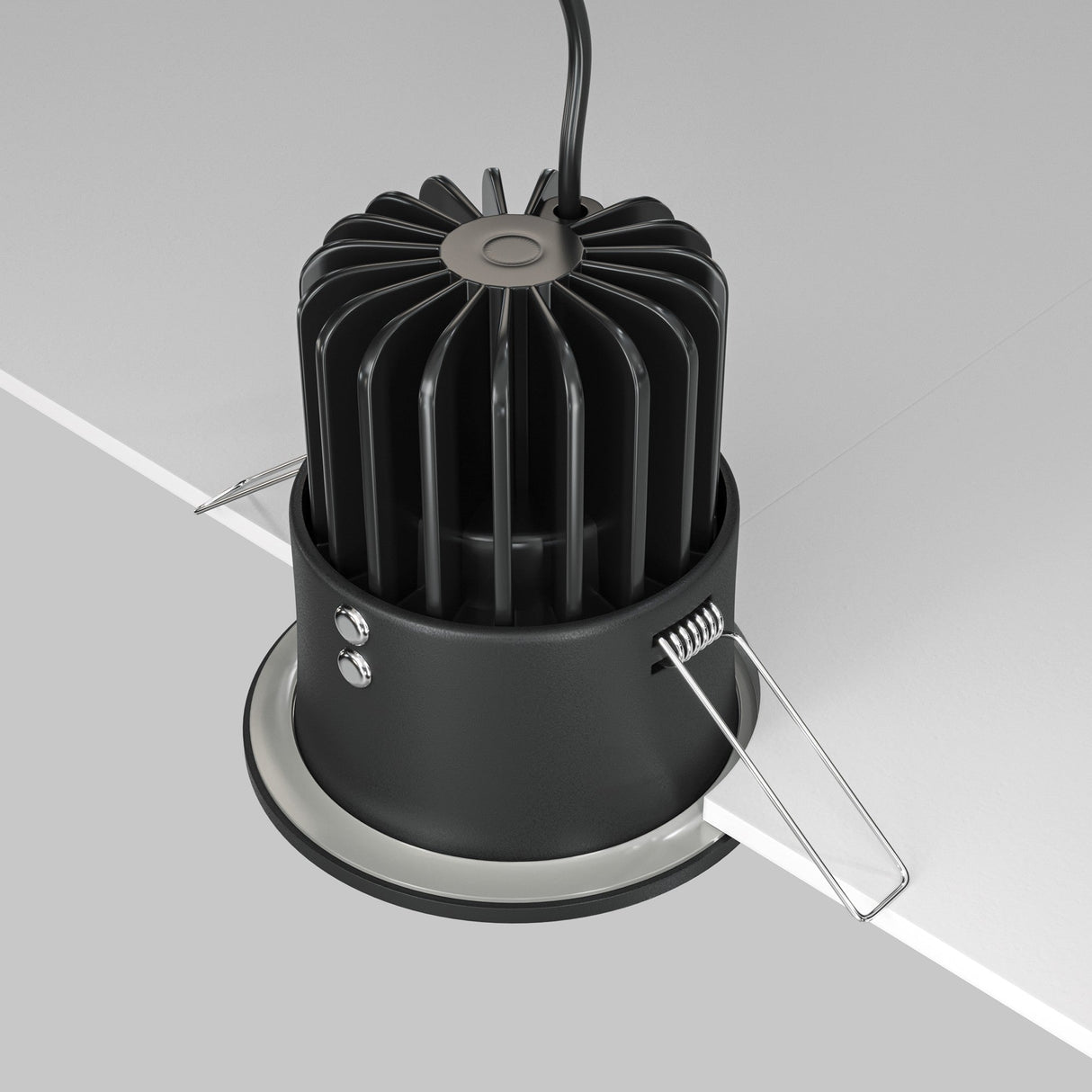 The Zoom LED Dimmable Round Recessed Downlight, 12W 4000K in black, is partially installed in a white ceiling. It includes vertical heat-dissipation fins, two mounting clips, and a top-attached cable. Its IP65 rating ensures durability while emitting crisp 4000K light.