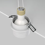 The Reif Round Recessed Downlight With Extended Rim - White & Gold is partially installed, featuring a circular housing with mounting clips and two wires extending from the top, neatly set against a white ceiling panel.