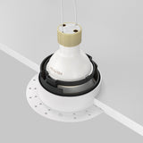 The Share Round Plaster-in Recessed Swivel Downlight - White is a ceiling-mounted fixture with a white base, designed for installation in white ceilings. It features an elegant plaster-in design, exposed wires at the top, and offers adjustable light direction for a modern, minimalistic appeal.