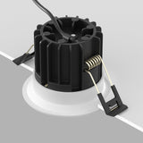 The Round LED Recessed Downlight 12W 3000K - White features visible wiring and metal spring clips, partially installed in a grey surface. Perfect for ceiling installation, this cylindrical fixture suits minimalist interiors and contemporary lighting schemes.