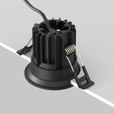 The Round LED Recessed Downlight 7W 3000K - Black features a close-up view of its ridged, cylindrical design with a spring-loaded clip for easy installation. Its sleek black finish and extending wire make it ideal for modern interior lighting.