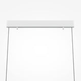The Motion LED Dimmable Linear Suspension Light - White features a sleek rectangular fixture, suspended by black wires. This minimalist design combines elegance with advanced LED technology for a sophisticated modern look.