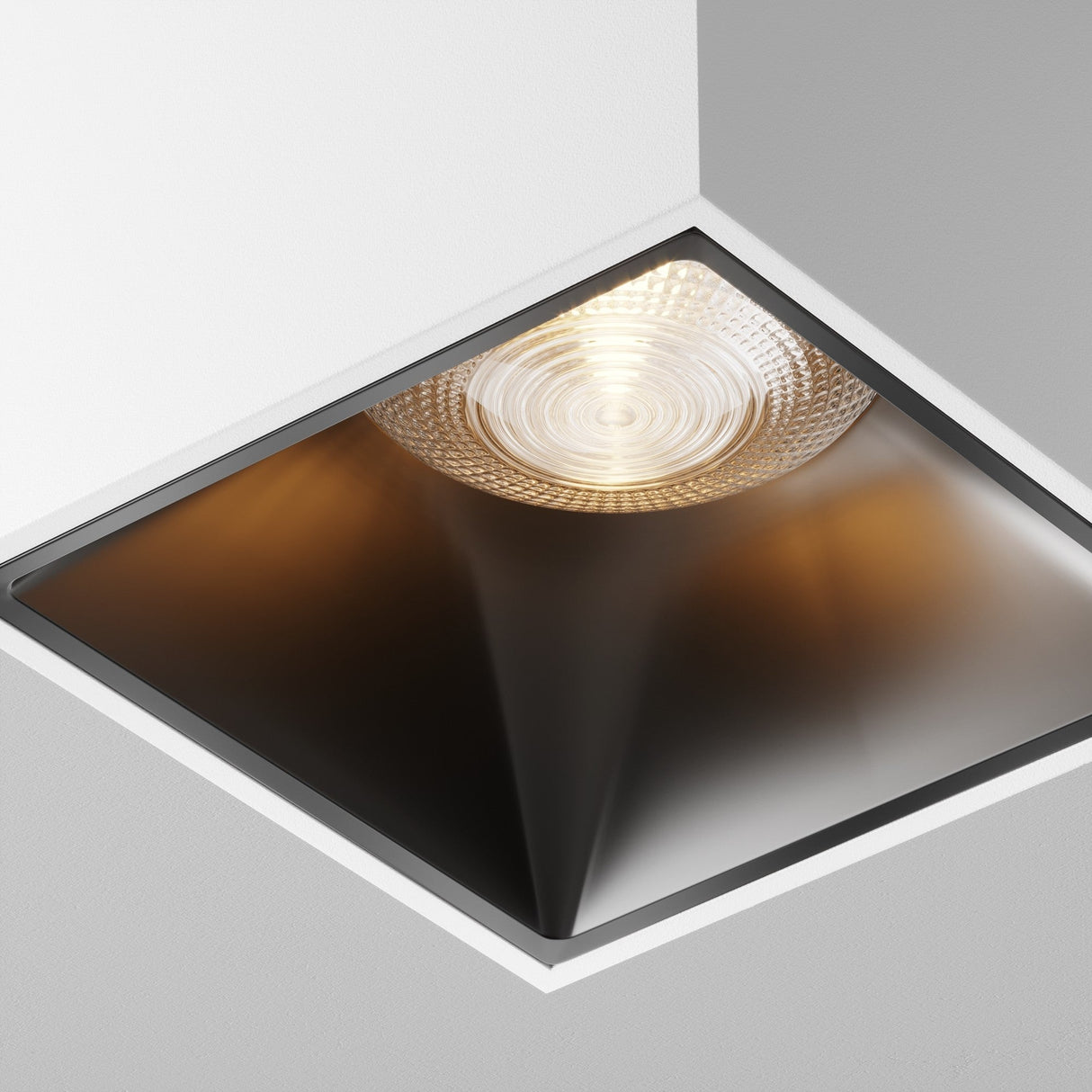The Alfa LED Square Surface Downlight 12W 3000K combines minimalist design with a square recessed frame, casting a warm glow that highlights the geometric structure and sleek black-and-white contrast of the ceiling.