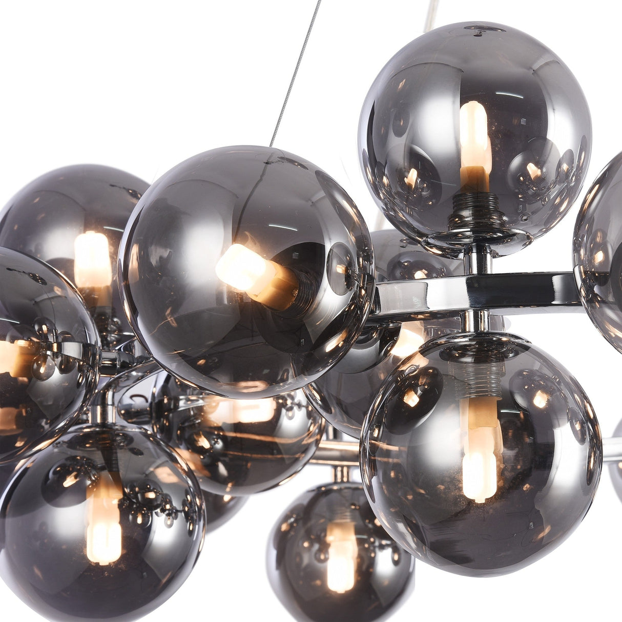 Close-up of the Dallas 25 Light Suspension - Chrome With Smoky Glass, highlighting smoky bulbs emitting a warm glow. These round, reflective bulbs are mounted on a sleek chrome frame, reflecting their surroundings for a dynamic visual effect.